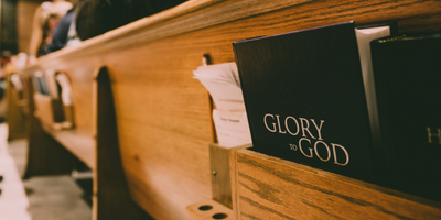 pew with a hymnal titled "Glory to God"